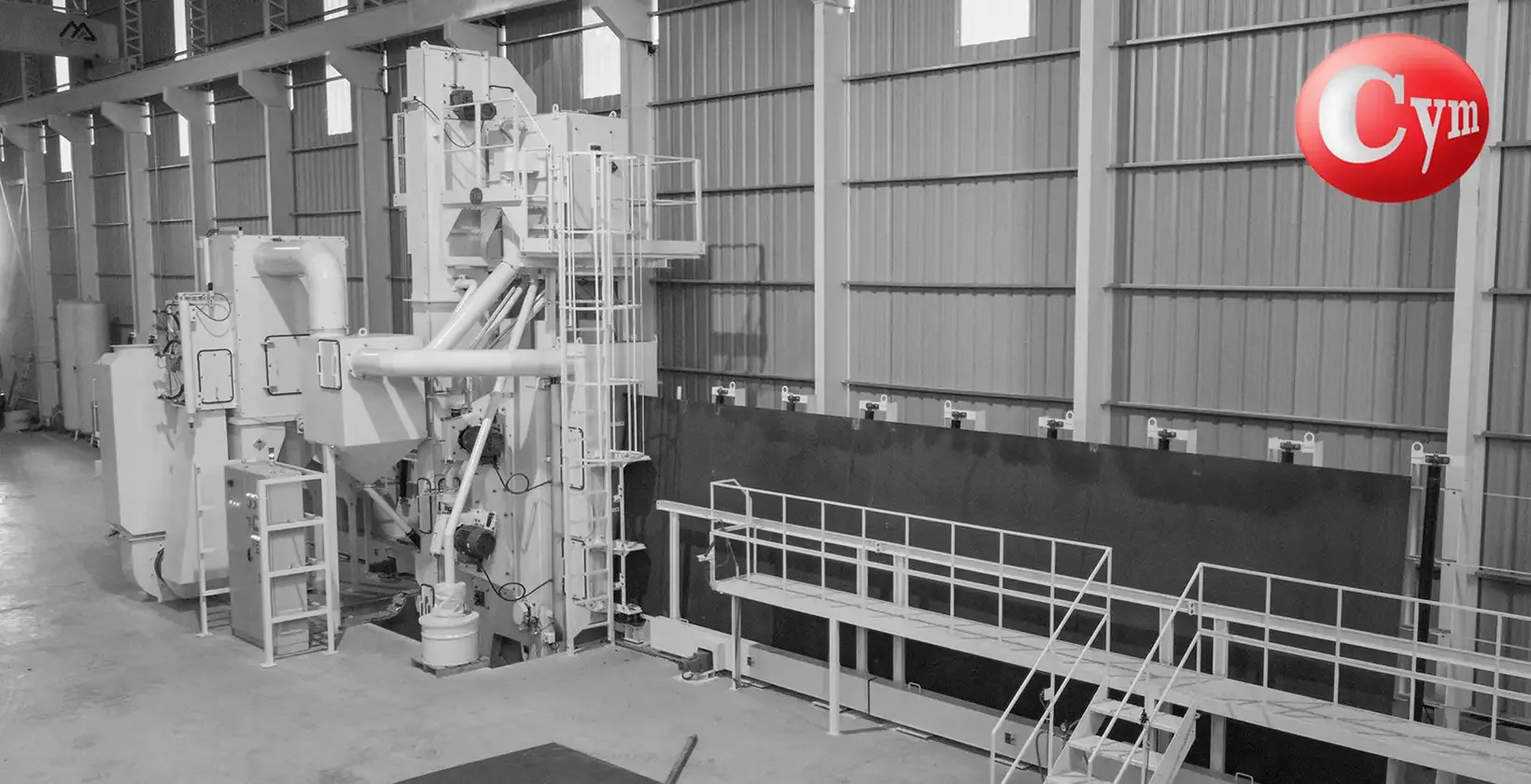 CYM vertical plate blaster – front view with vertical infeed conveyor carrying black steel plates (with mill scale) on the right