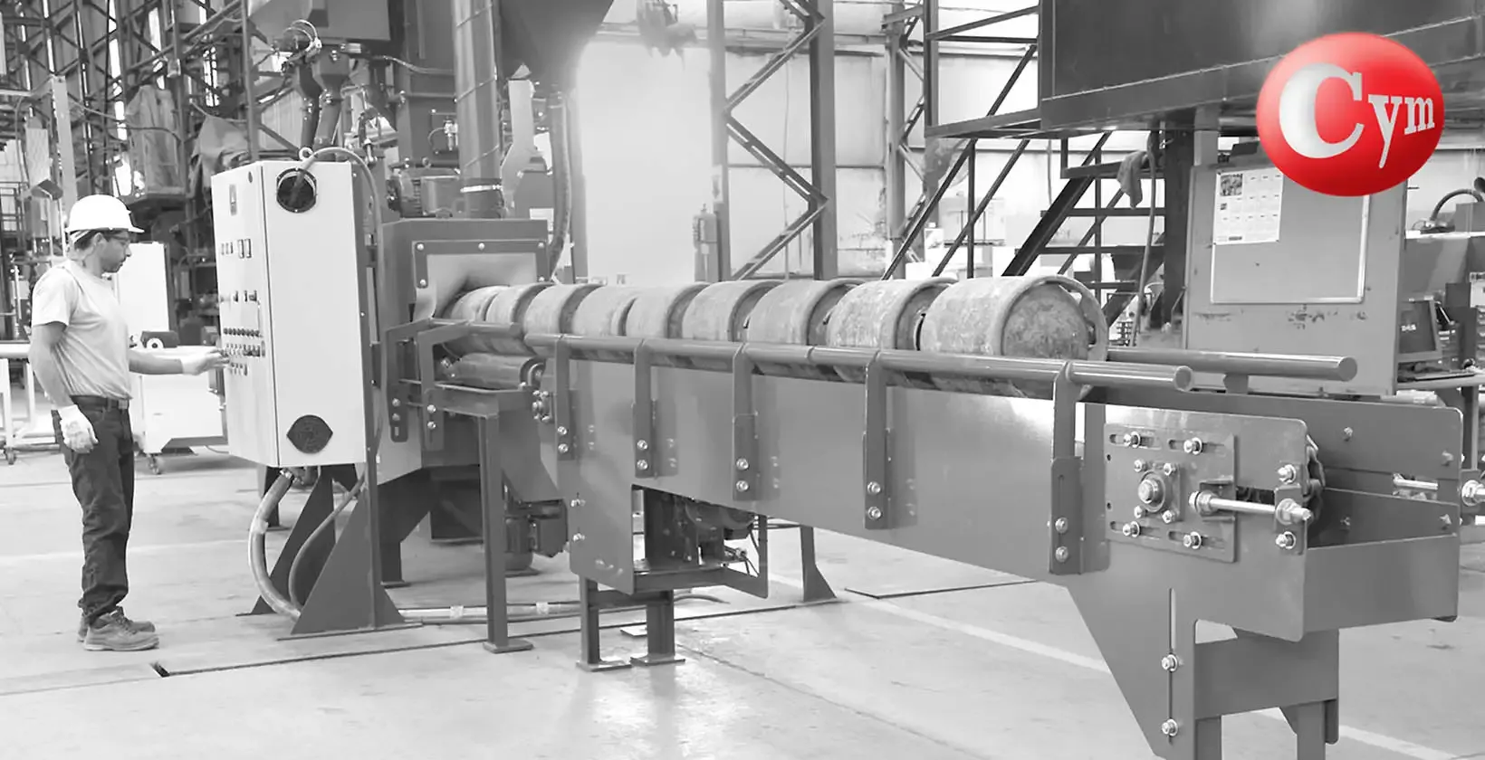 CYM GAR 200-RI blast machine – external chain conveyor with LPG cylinder at entry, operator at control panel · CYM, Argentina