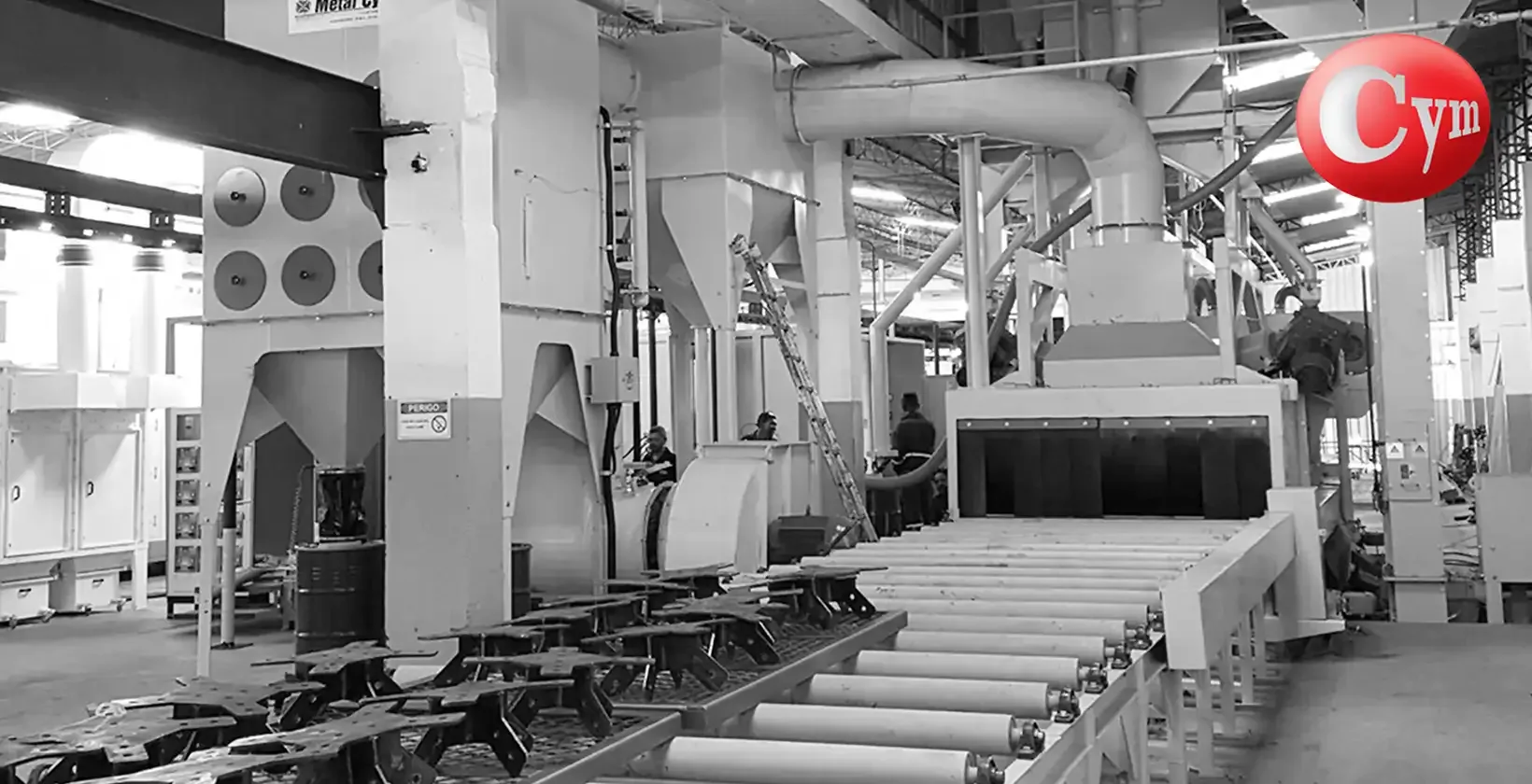 CYM PER-I 21x8 – 83" × 31" (2,100 × 800 mm) – angled blast wheels – view from infeed conveyor with welded structure entering blast cabinet