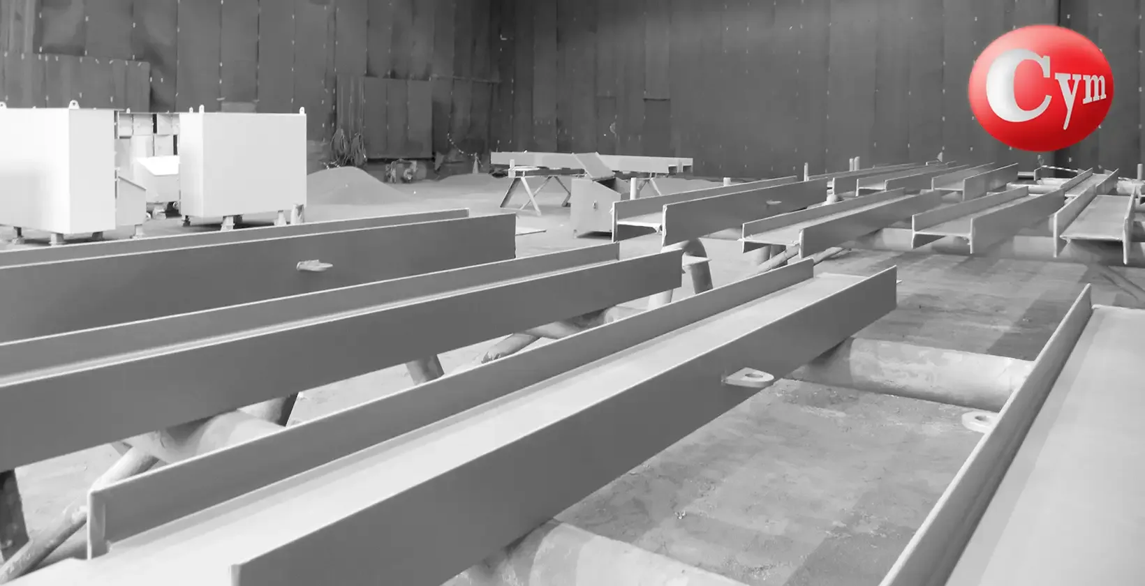 Interior cuarto granallado CYM Materiales BrasFELS Brasil — perfiles vigas acero sobre tarimas industria naval