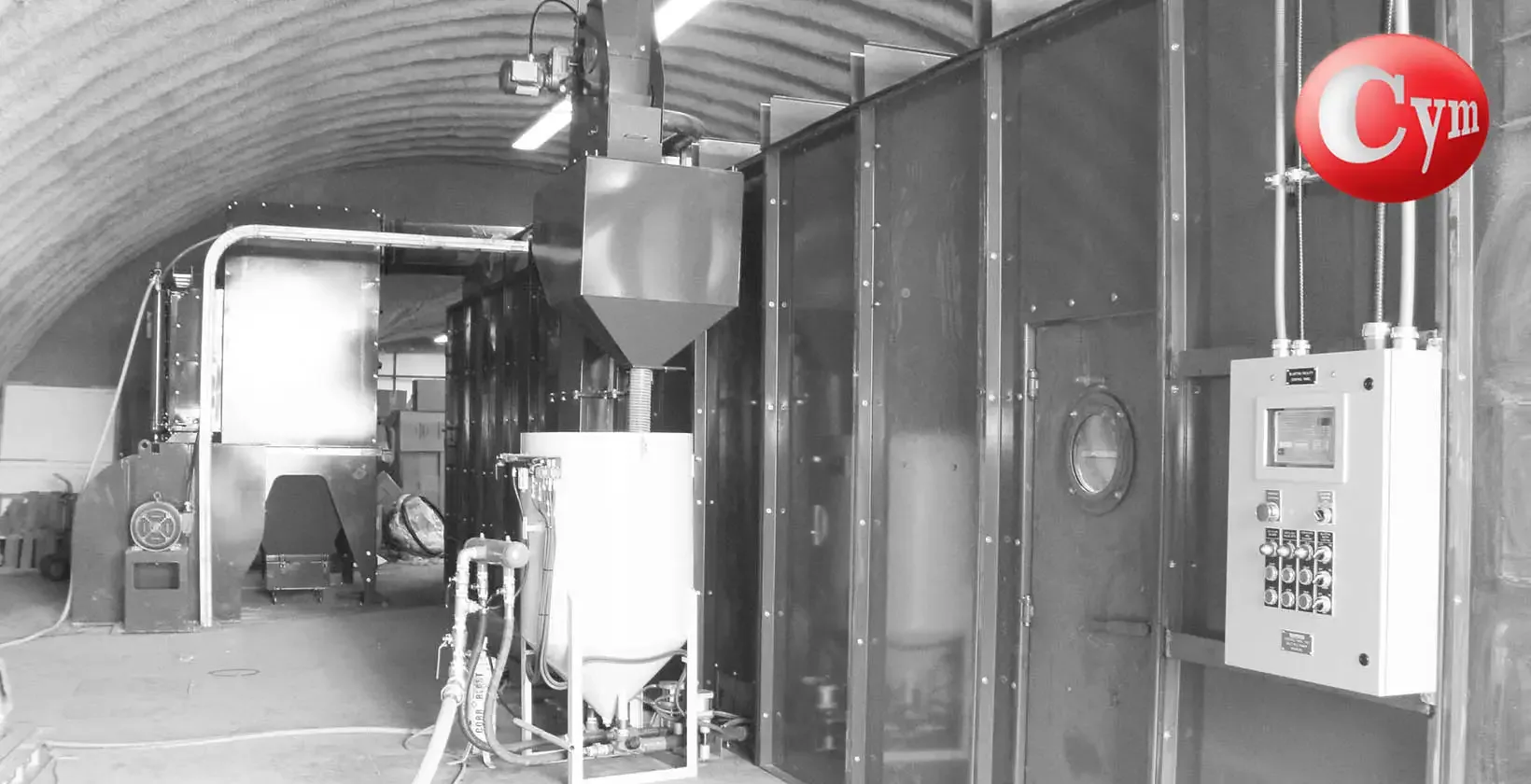 CYM Materiales portable abrasive air wash separator installed in hangar-type blast room with hopper and control panel